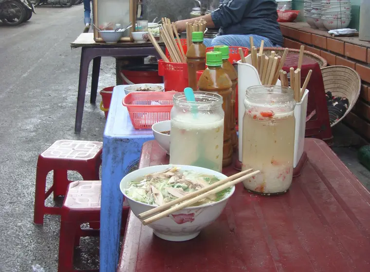Street vendor serving pho ga from a pavement stall in Hanoi