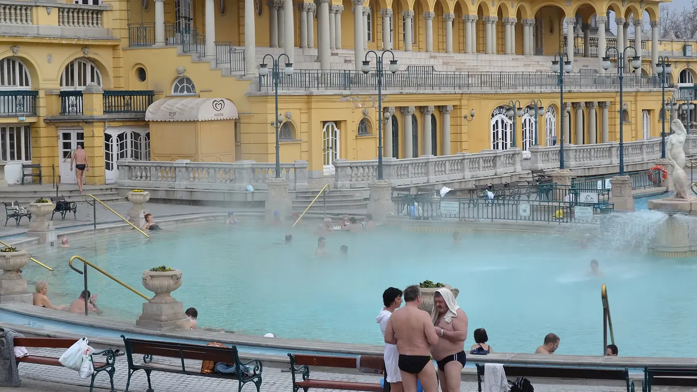 The outdoor pools and yellow neo-baroque facade of the Széchenyi thermal bath in Budapest